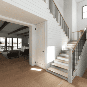 A modern farmhouse interior featuring an open living area, well-lit with natural light, hardwood floors, and a staircase with white railings. Large windows enhance the welcoming atmosphere.