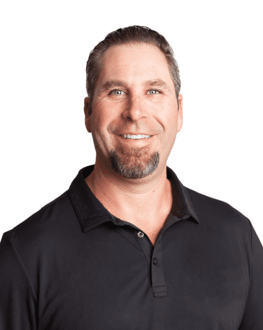 Meet Your Team: A man with short hair and a goatee is smiling, wearing a black polo shirt against a plain white background.